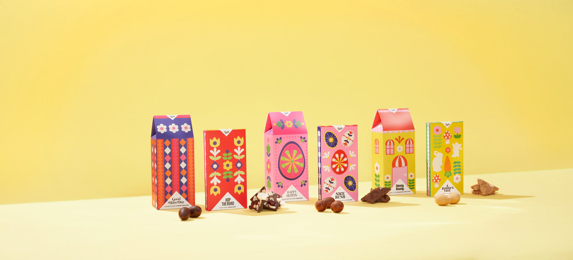 Colourful packaging design for a collection of chocolate bars, photographed against a yellow background and featuring folk art-inspired papercraft collage illustration in various Easter-themed motifs.